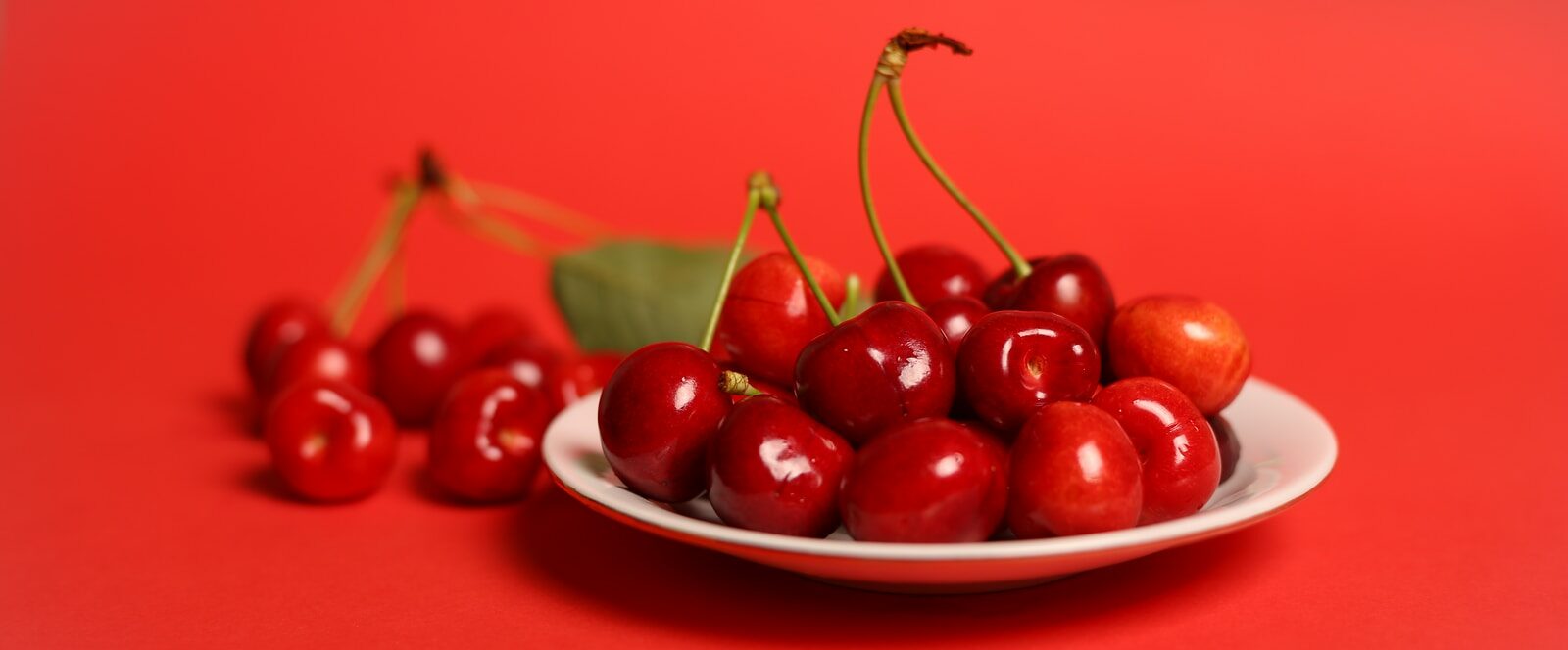red cherry fruits on white ceramic bowl