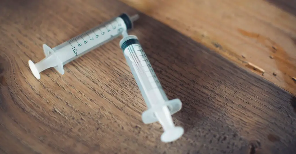 white and black plastic syringe on brown wooden table