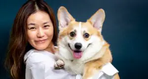 woman in white shirt holding brown and white dog